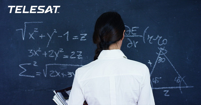 woman at chalkboard with back to camera writing out formula