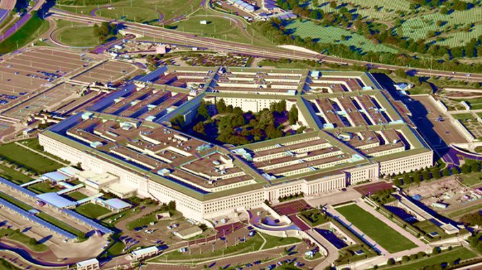 An image of Pentagon buildings captured from the bird view. We can see brown roof tops and green fields around.